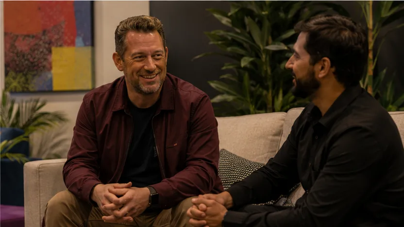 Two attendees talking on a sofa inside the Oasis lounge
